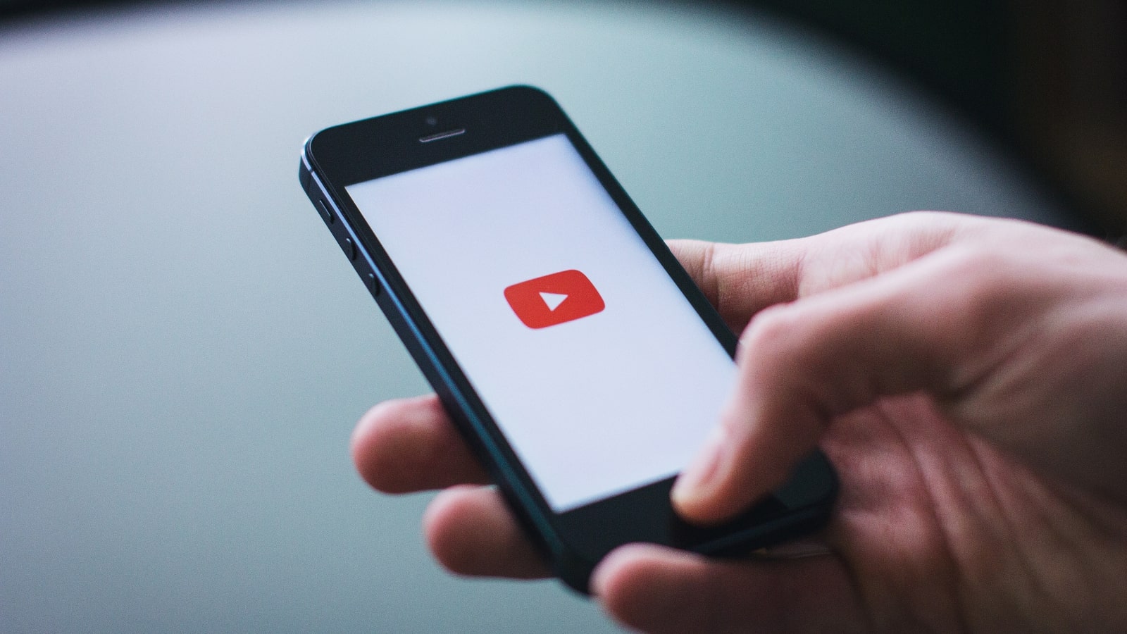 Close-up image of hand opening youtube app on phone.