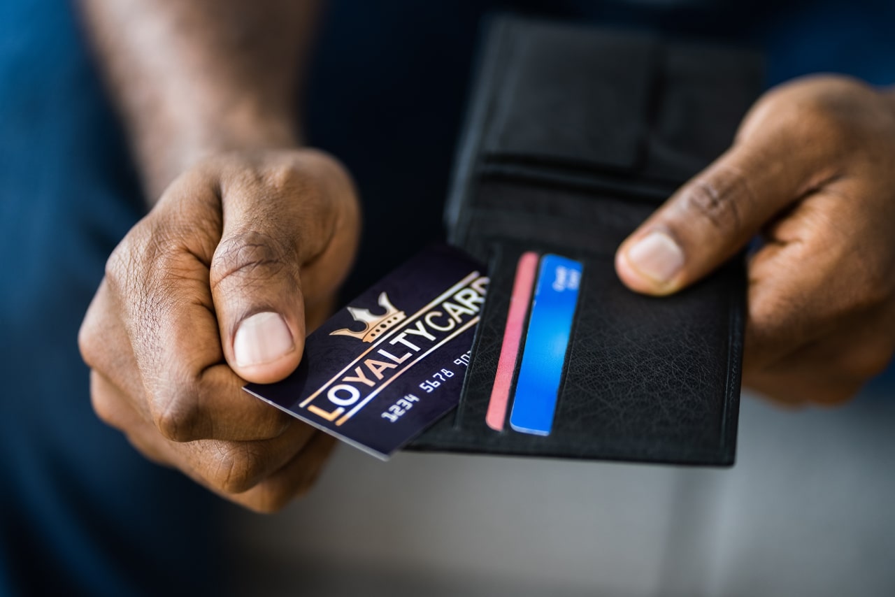 Close-up of a male person taking out his loyalty card from his wallet.
