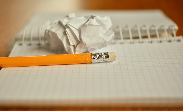 Crumpled paper, notebook and pencil on desk.