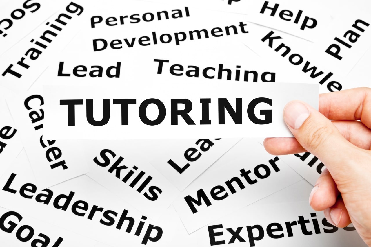 Hand holding a piece of paper with Tutoring written on it.