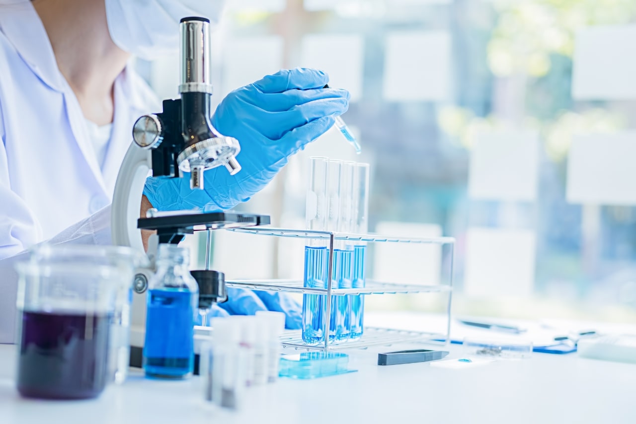 Medical person looking at a clear test tube.