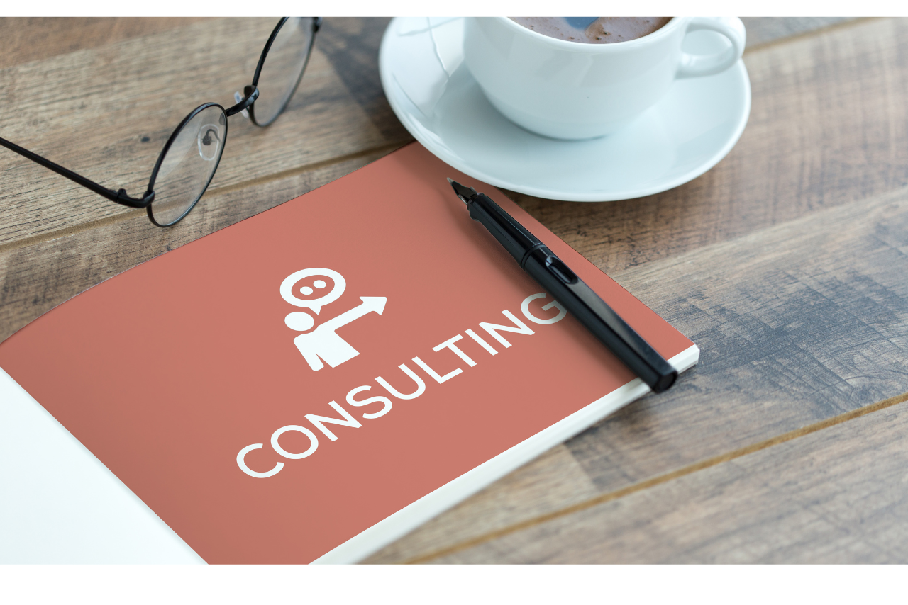 Open book with consulting word besides coffee, pen and glasses.