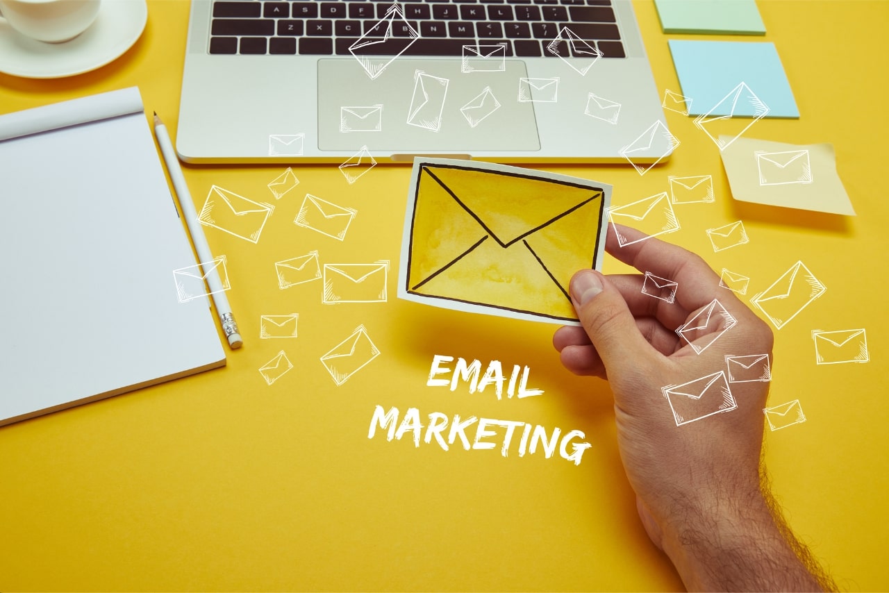 Person holding paper envelope with email icons around.