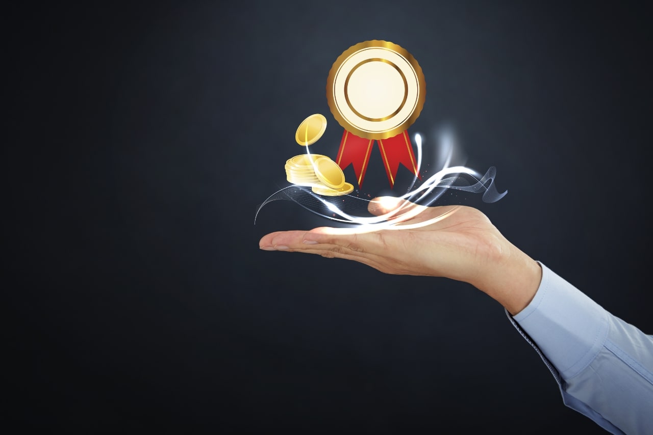 Person's open hand with gold & red ribbon and coins levitating.