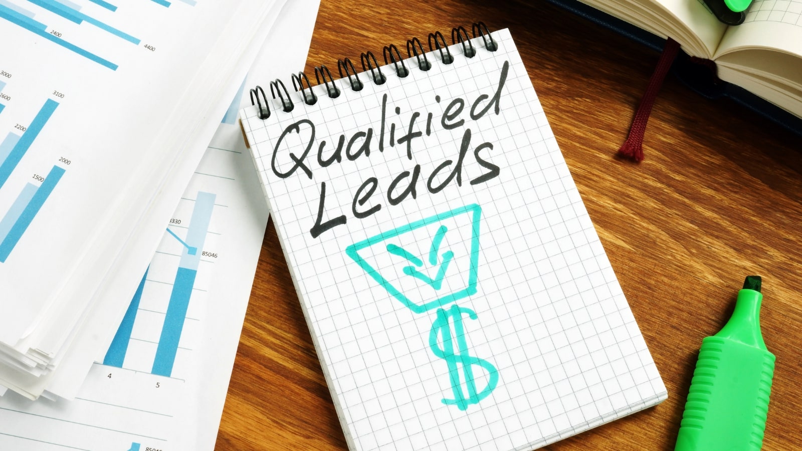 Qualified leads handwritten on a page and business papers.