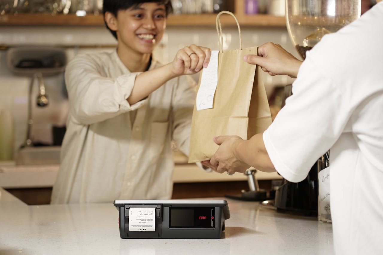 Staff smiling and giving a paper bag to a customer