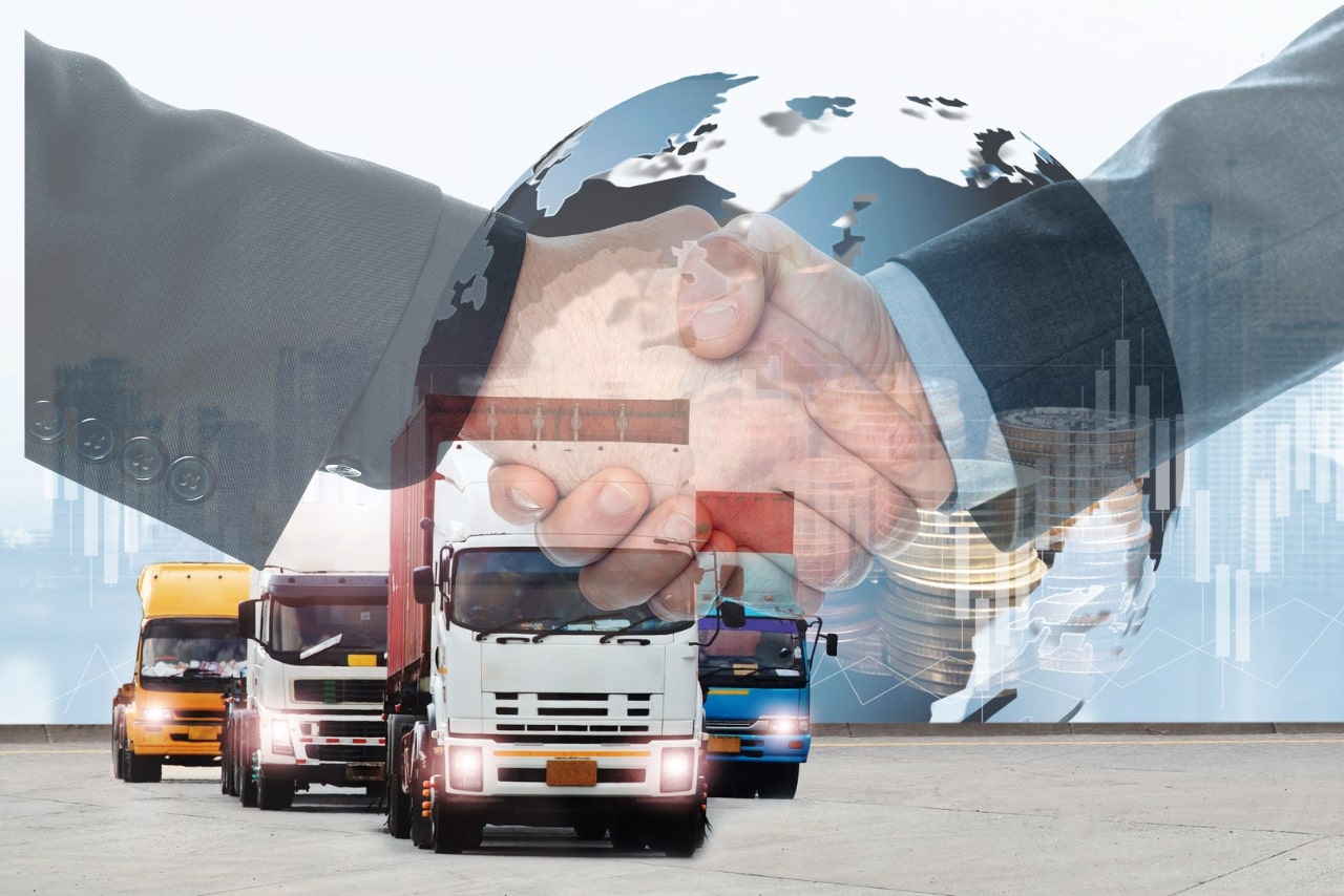Two businessmen shaking hands with logistics trucks on the background.