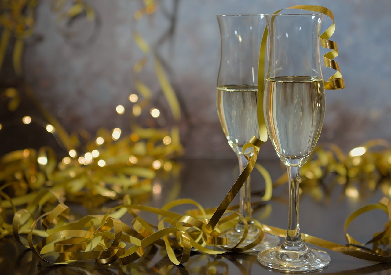 Two glasses of champagne surrounded by gold ribbons