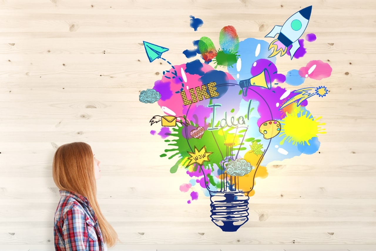 Woman looking towards illustration of a big lightbulbe signifying creativity and design skills.