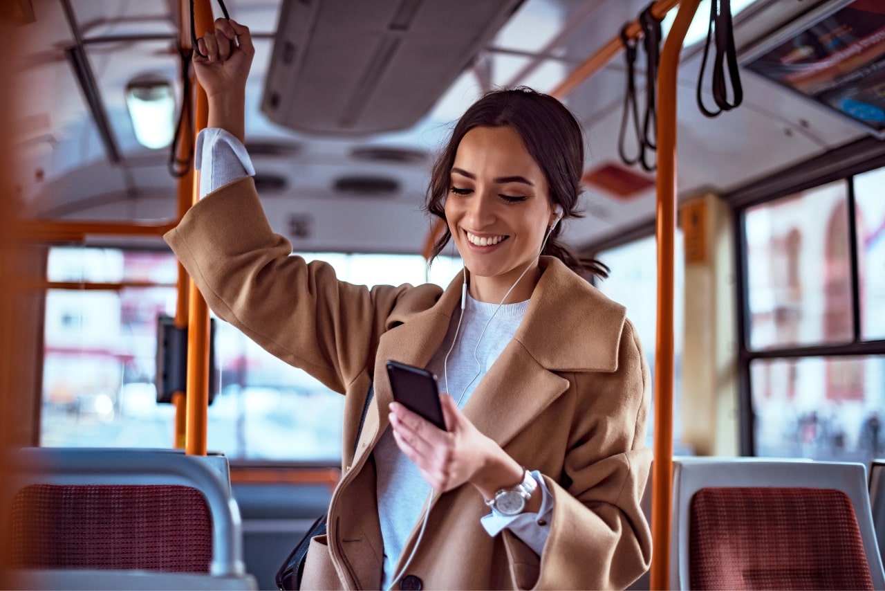 Woman riding on a bus while texting on phone.