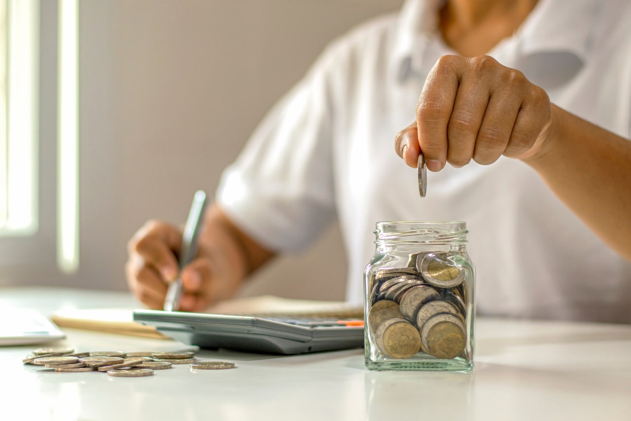 Woman saving coins on a piggy bank.