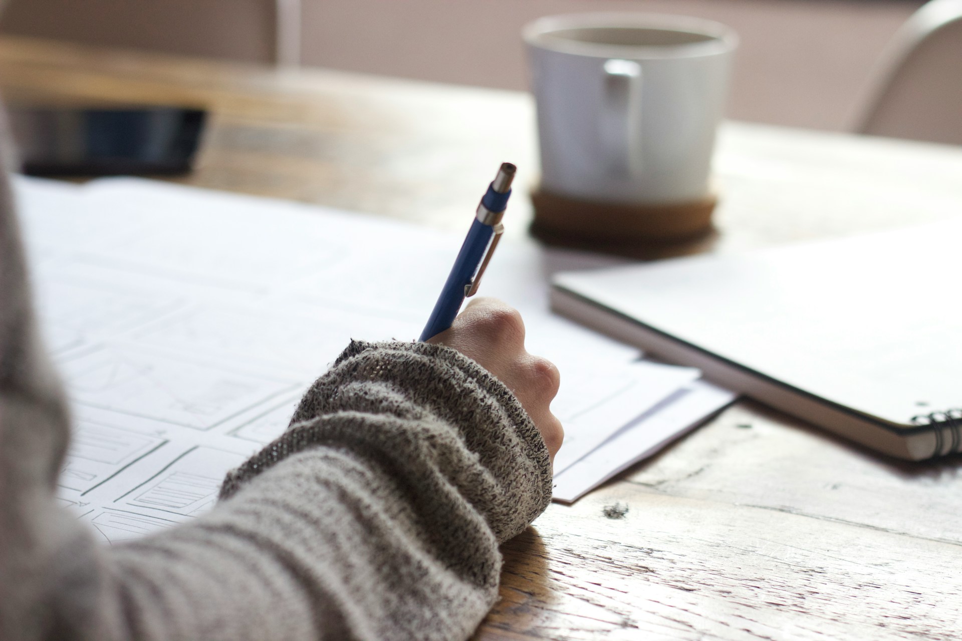 A close-up of a person's hand writing notes with a pen.