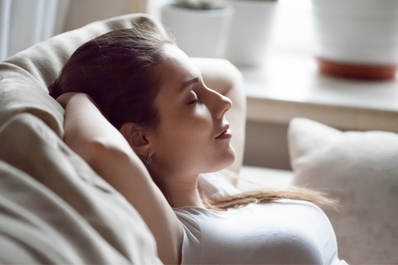 Calm woman relaxing on sofa with hands over head.