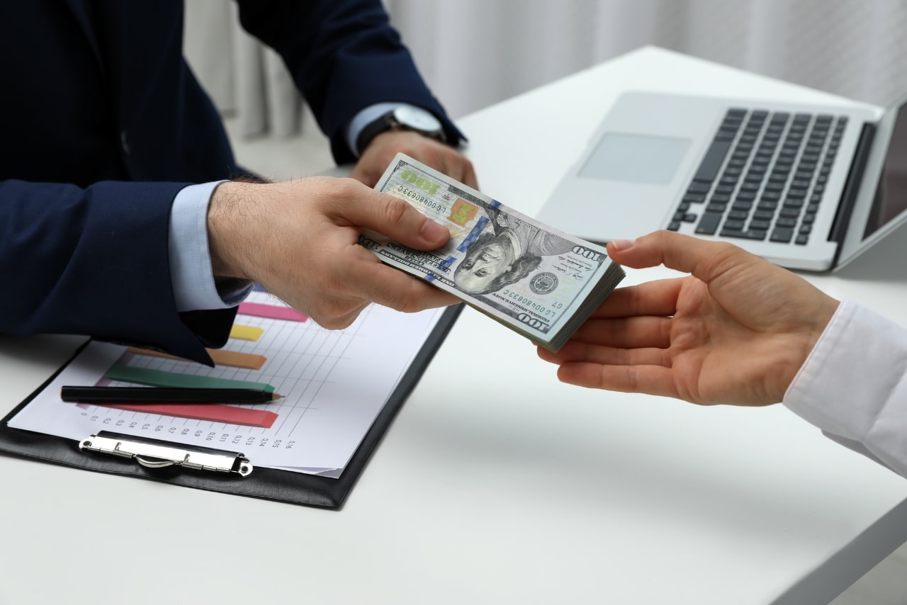 Person handing over cash to another person.