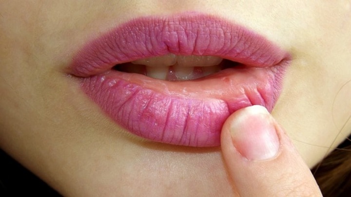 Pink lipstick applied to lips.