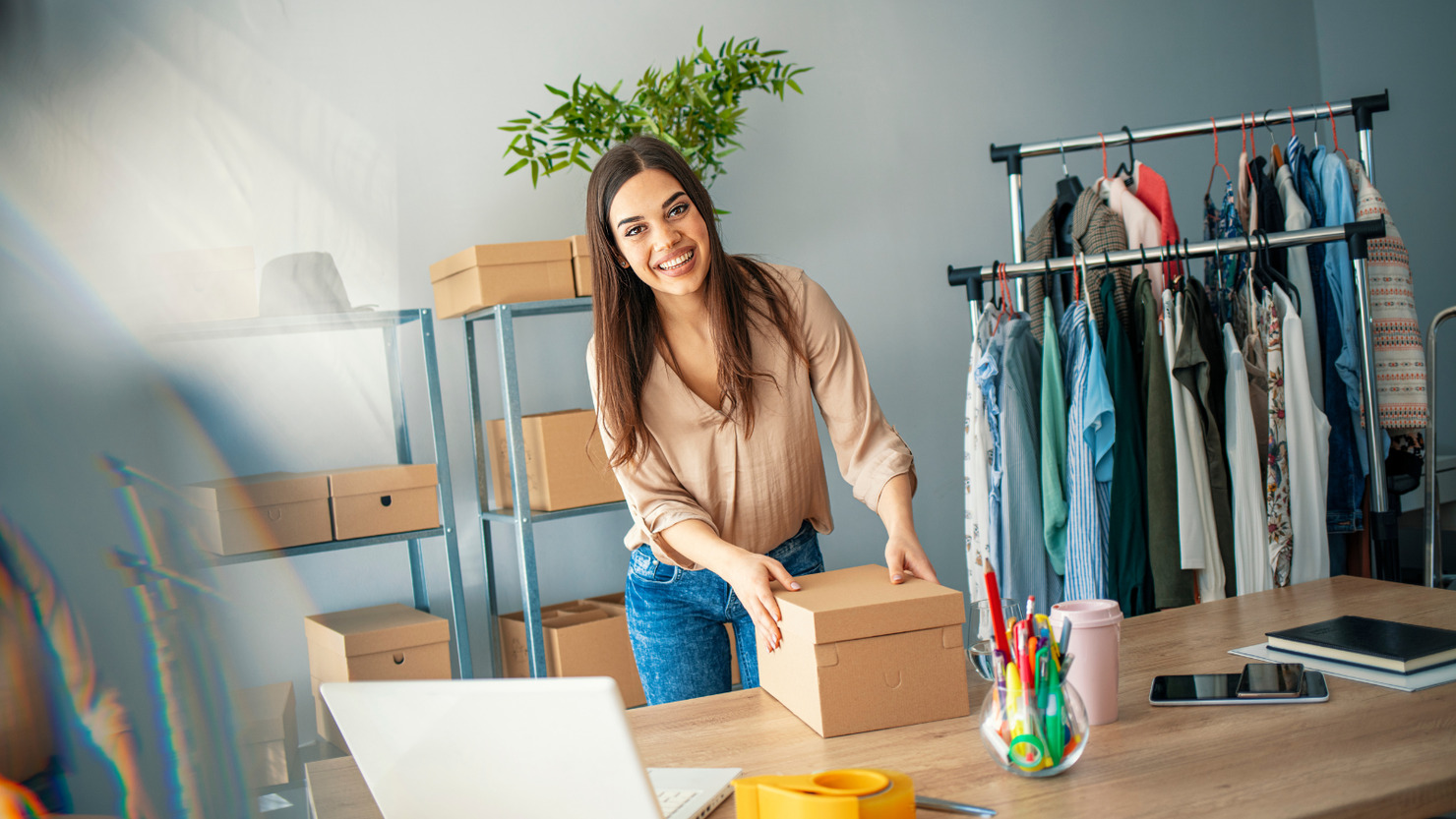 Happy female business owner packing order for her dropshipping business.