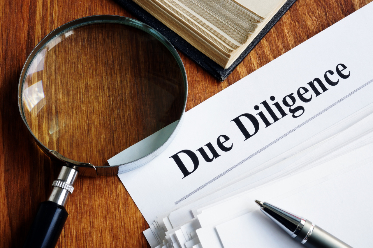 Stack of Due Diligence documents and magnifying glass.