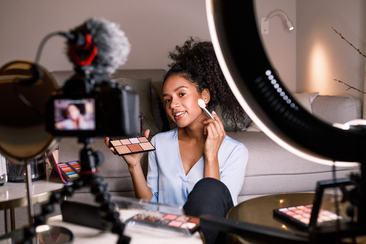 A beautiful young woman with a deep skin tone carefully applies makeup to her face.
