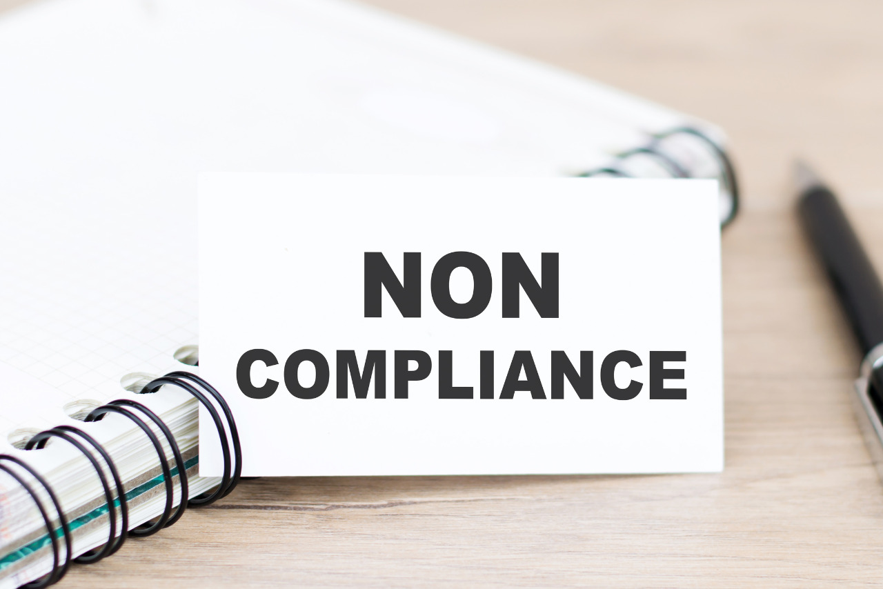 Text NON COMPLIANCE on the white paper note list.