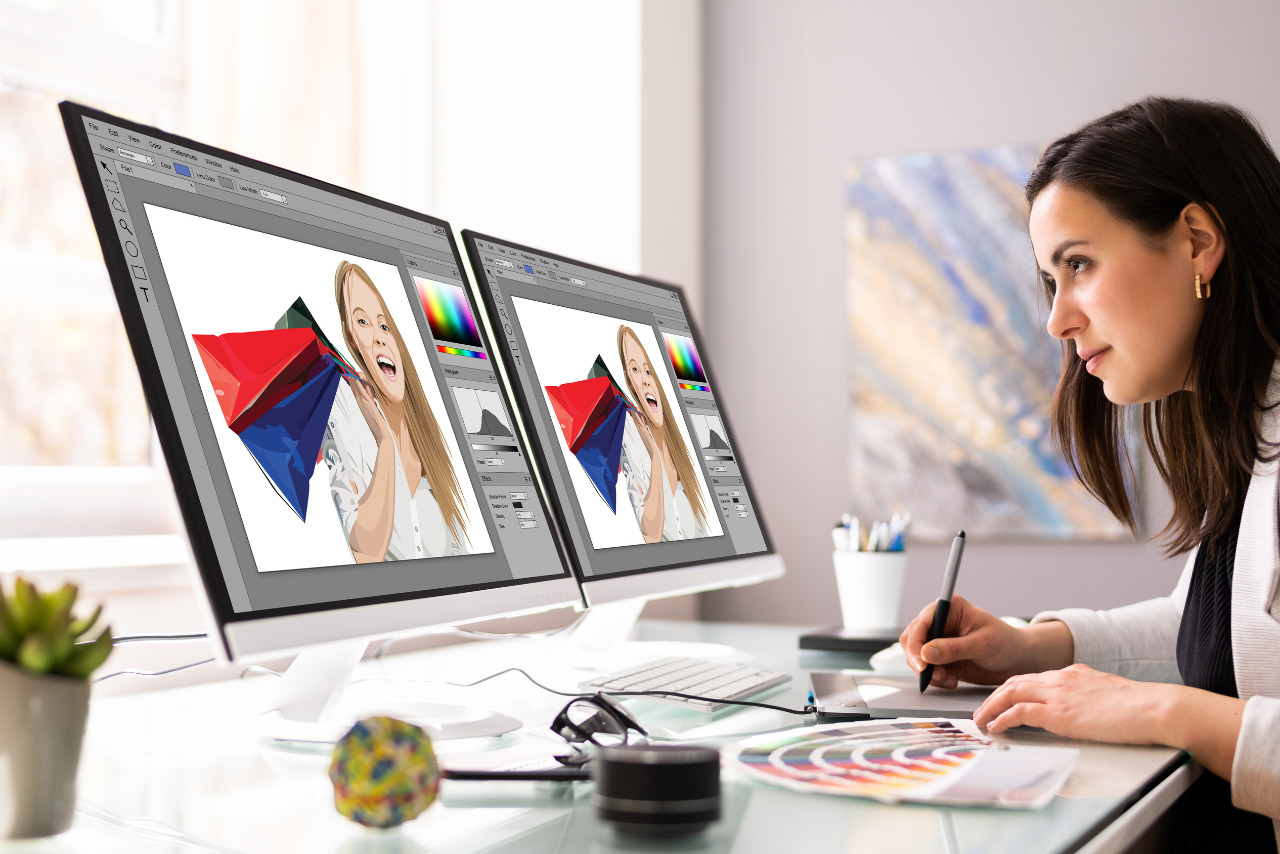 Female graphic designer working on fashion portfolio on multiple computers.