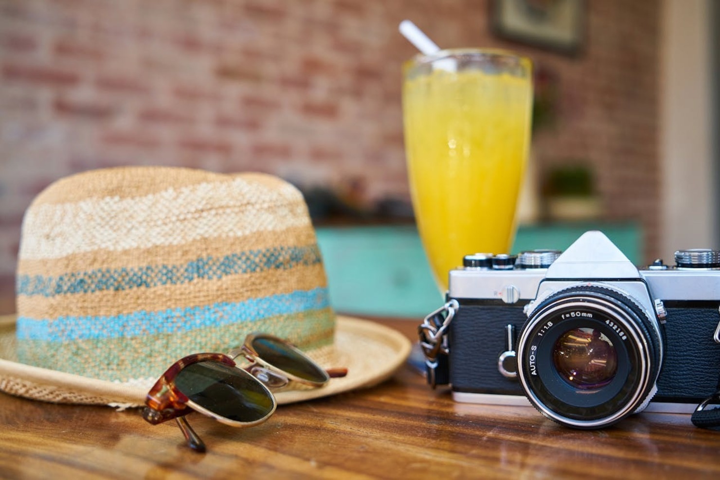 Travel essentials - a camera, eyeglasses, and a hat on a table