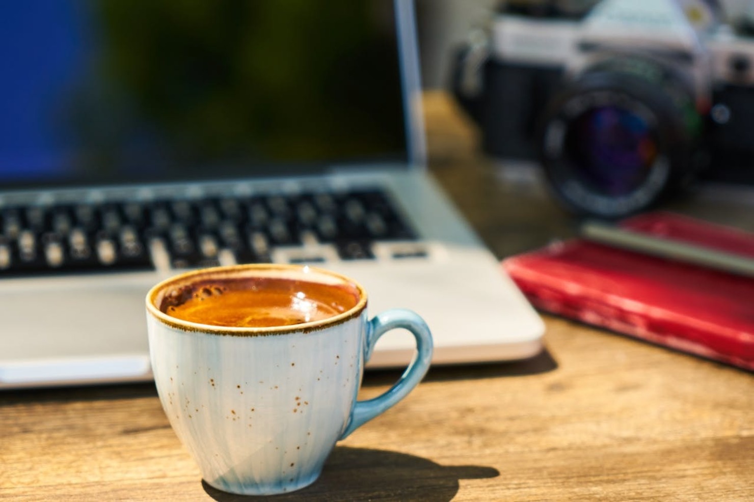 A cup of coffee and a laptop placed on a wooden table