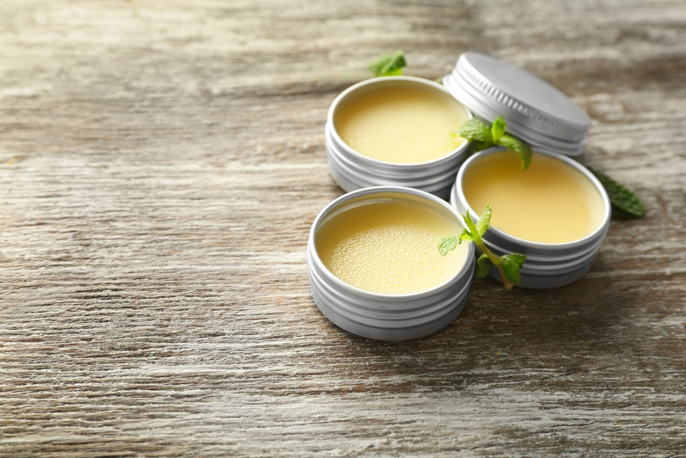 Containers with Lemon Balm Salve and Leaves on Table.