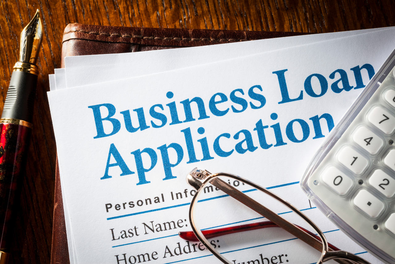 Business Loan Application paper with glasses and calculator.