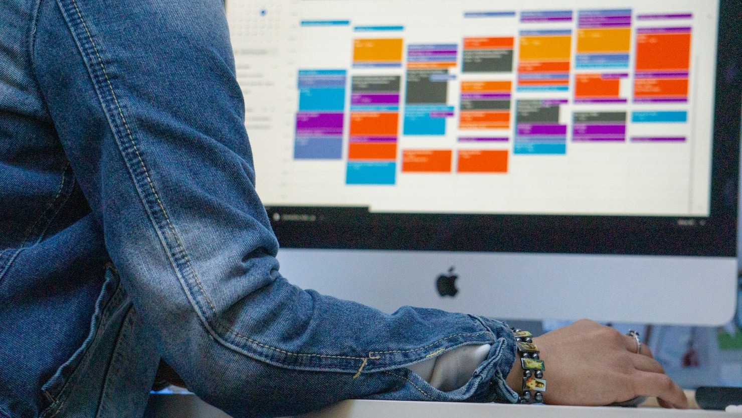 A man looking at his color-coded calendar on his computer