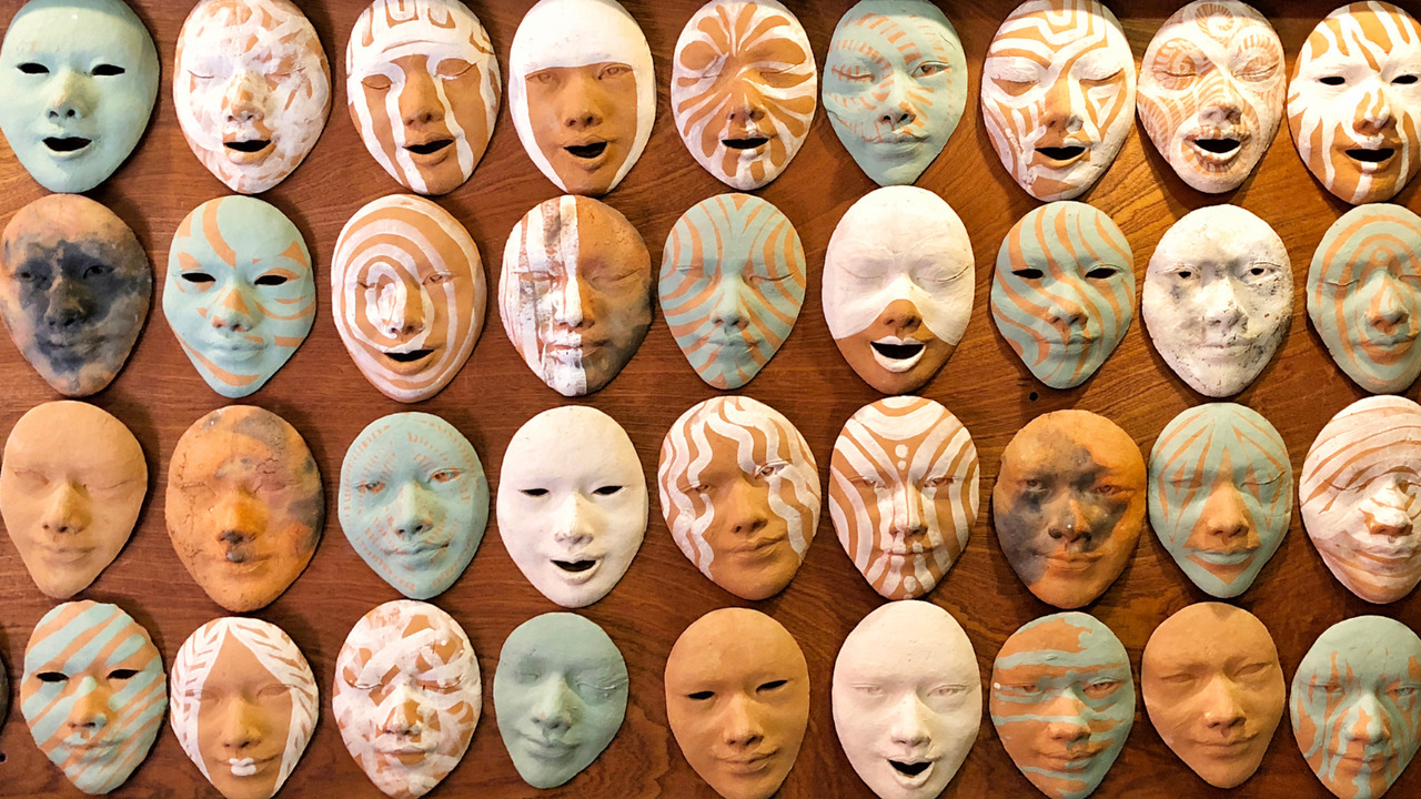 Old masks on wall with different emotions.
