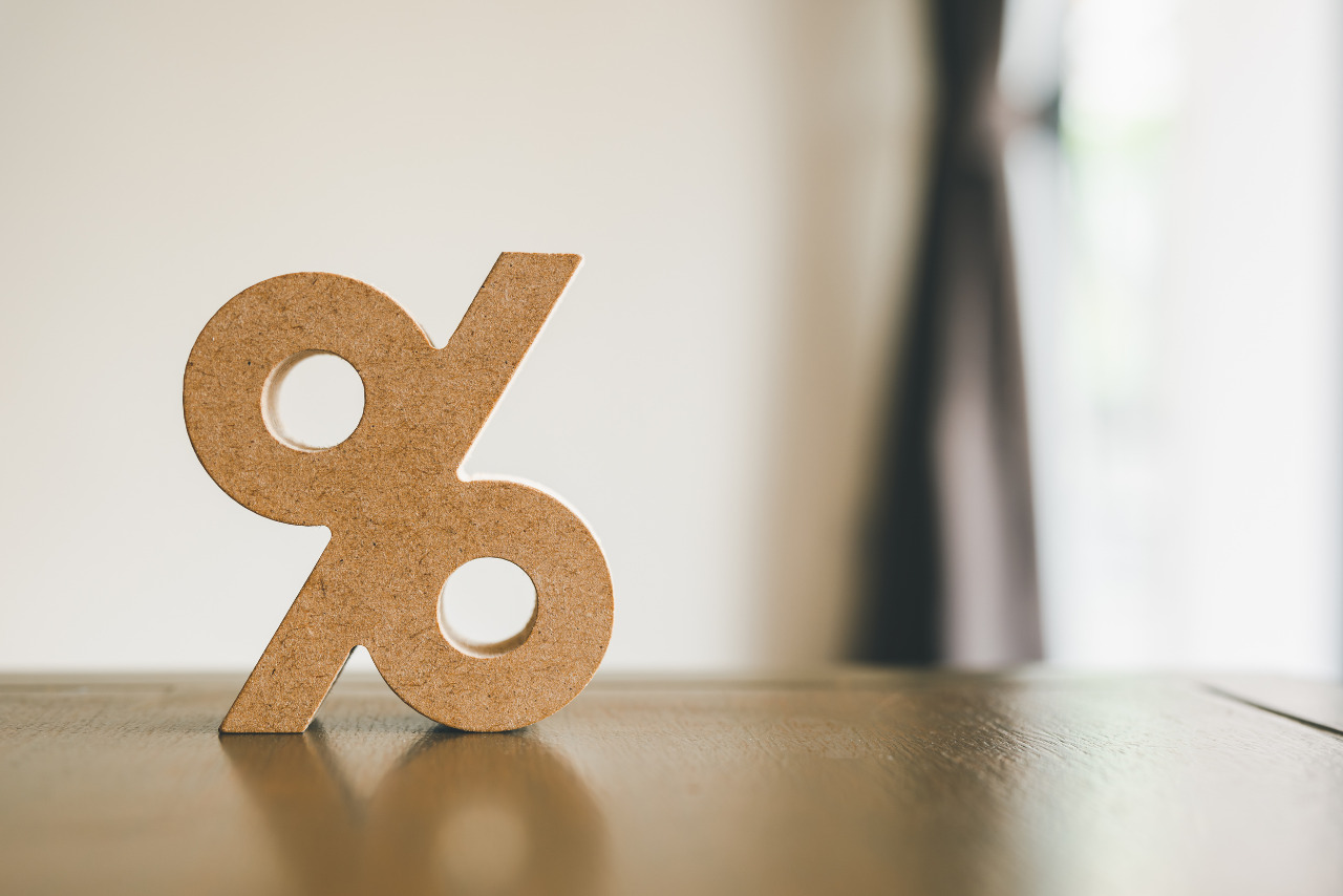 Cardboard percentage sign standing alone on table.