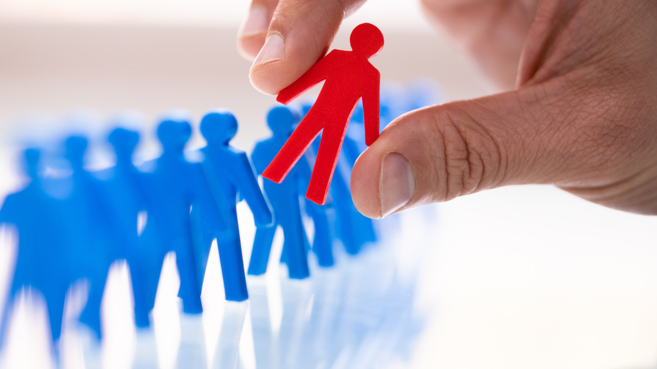 Selecting a red figurine from among blue ones, symbolizing the search for an ideal client.