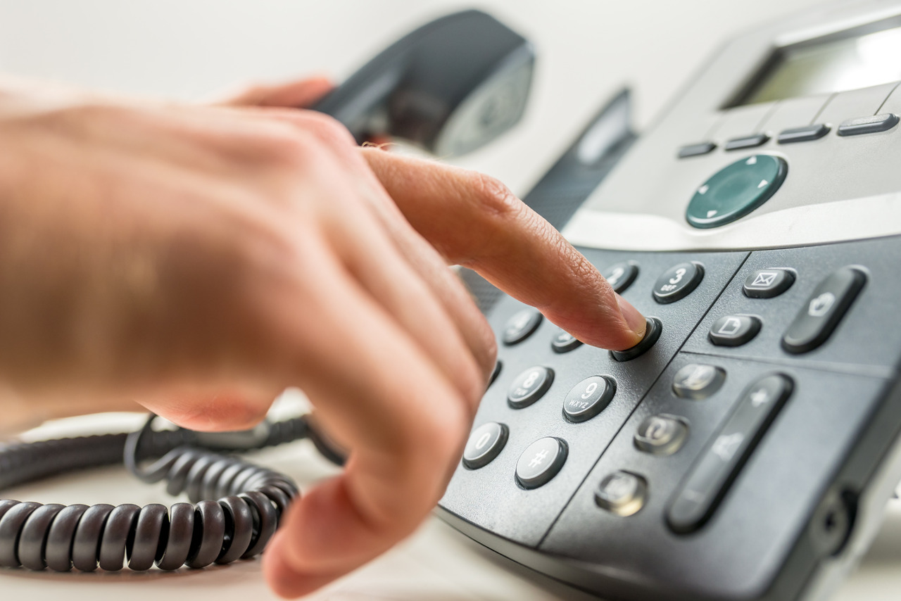 Hand dialing on telephone to call business establishment.