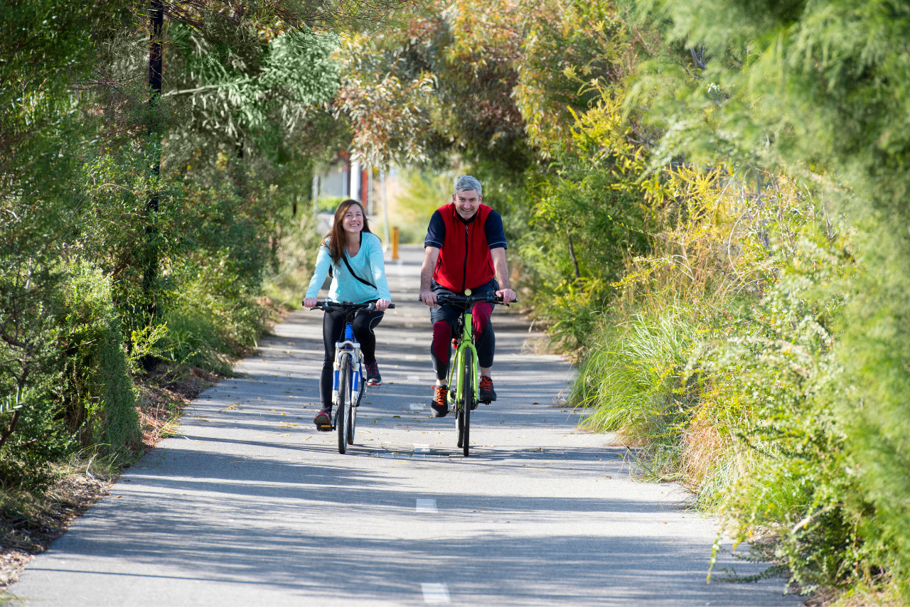 Couple cycling along road in urban fringe.