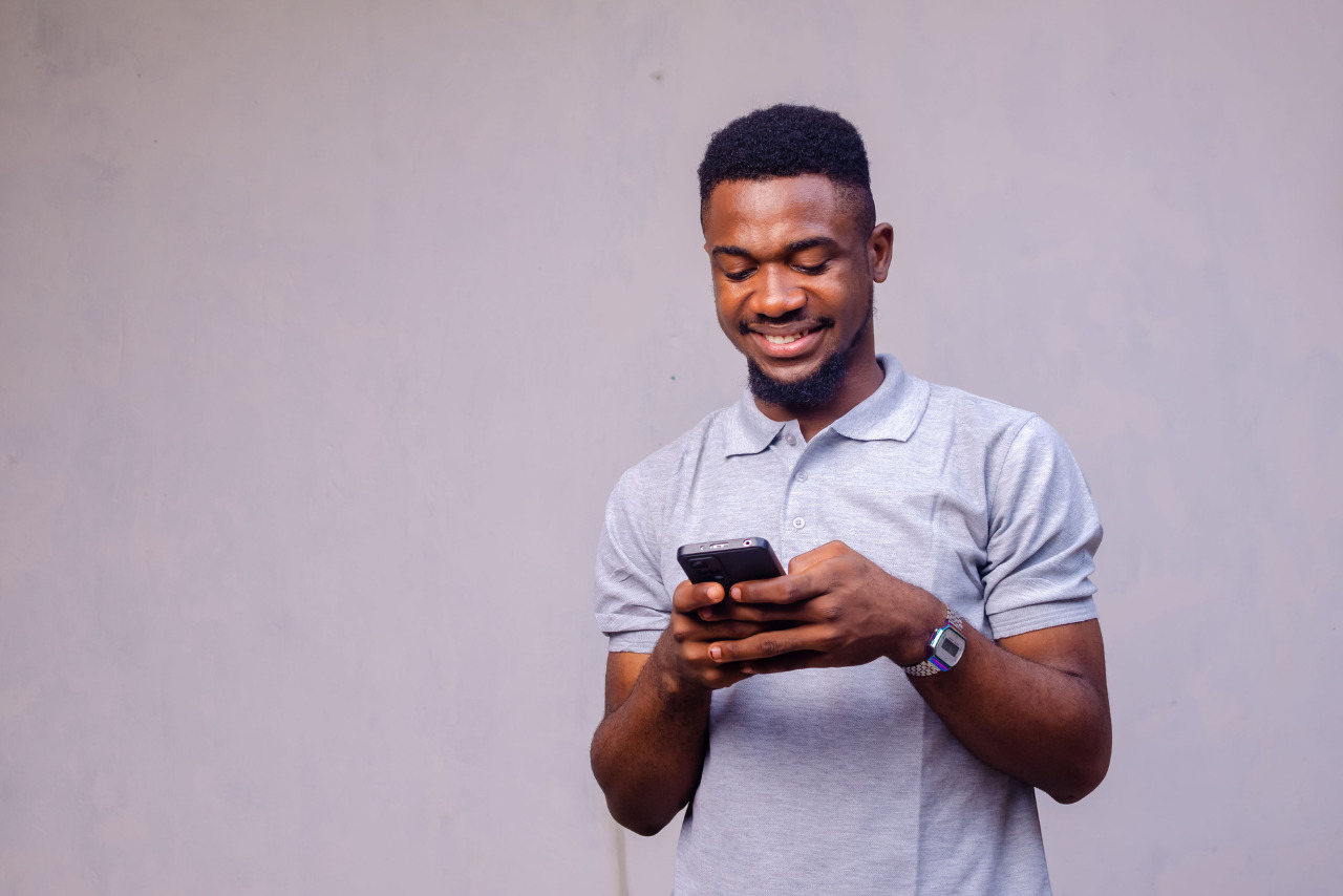 A man grinning and fully engaged with his mobile phone during an hourly sale.