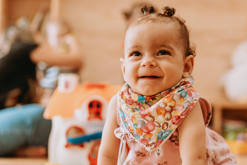 A baby girl wearing a bib and smiling.