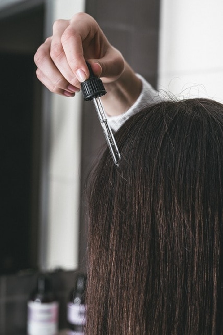 A woman applying serum to enhance hair health.
