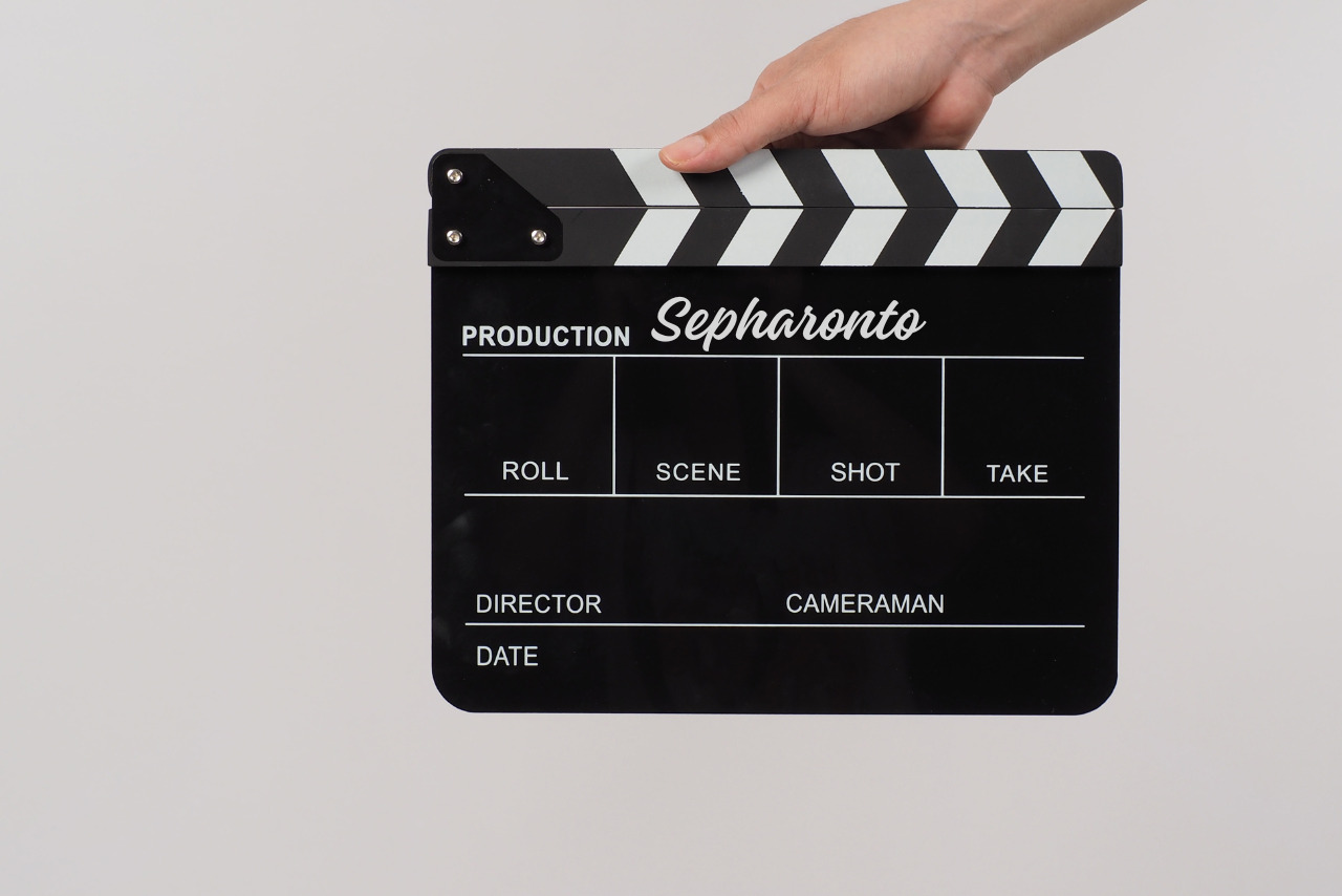Hand holding clapperboard with production name written on it.