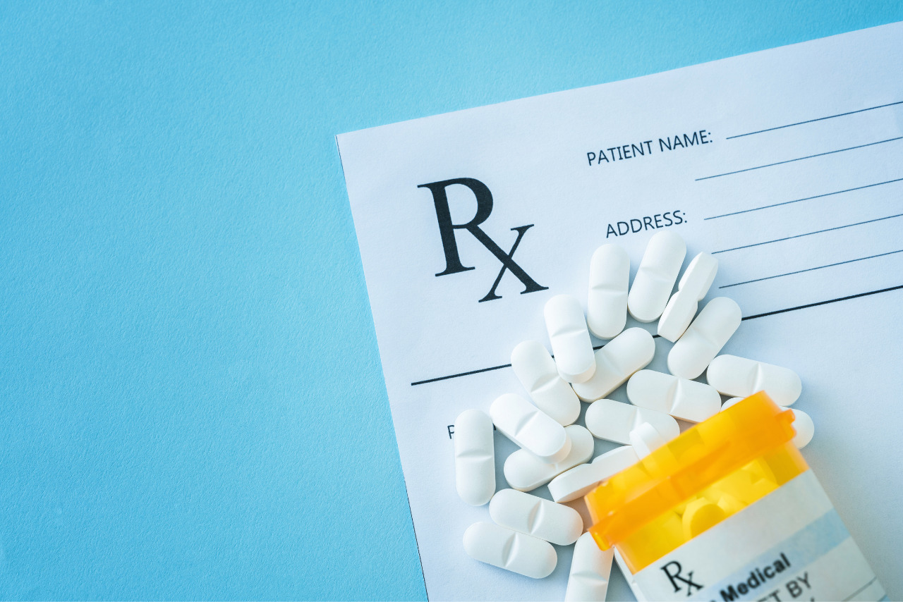 A blank prescription form with pills on a table.