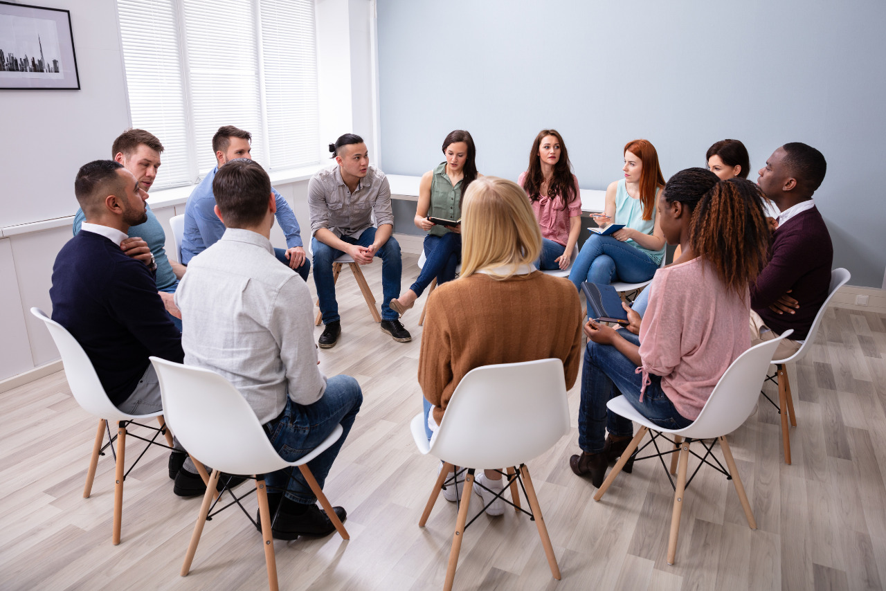 A diverse group of people sitting in a circle participating in counseling.