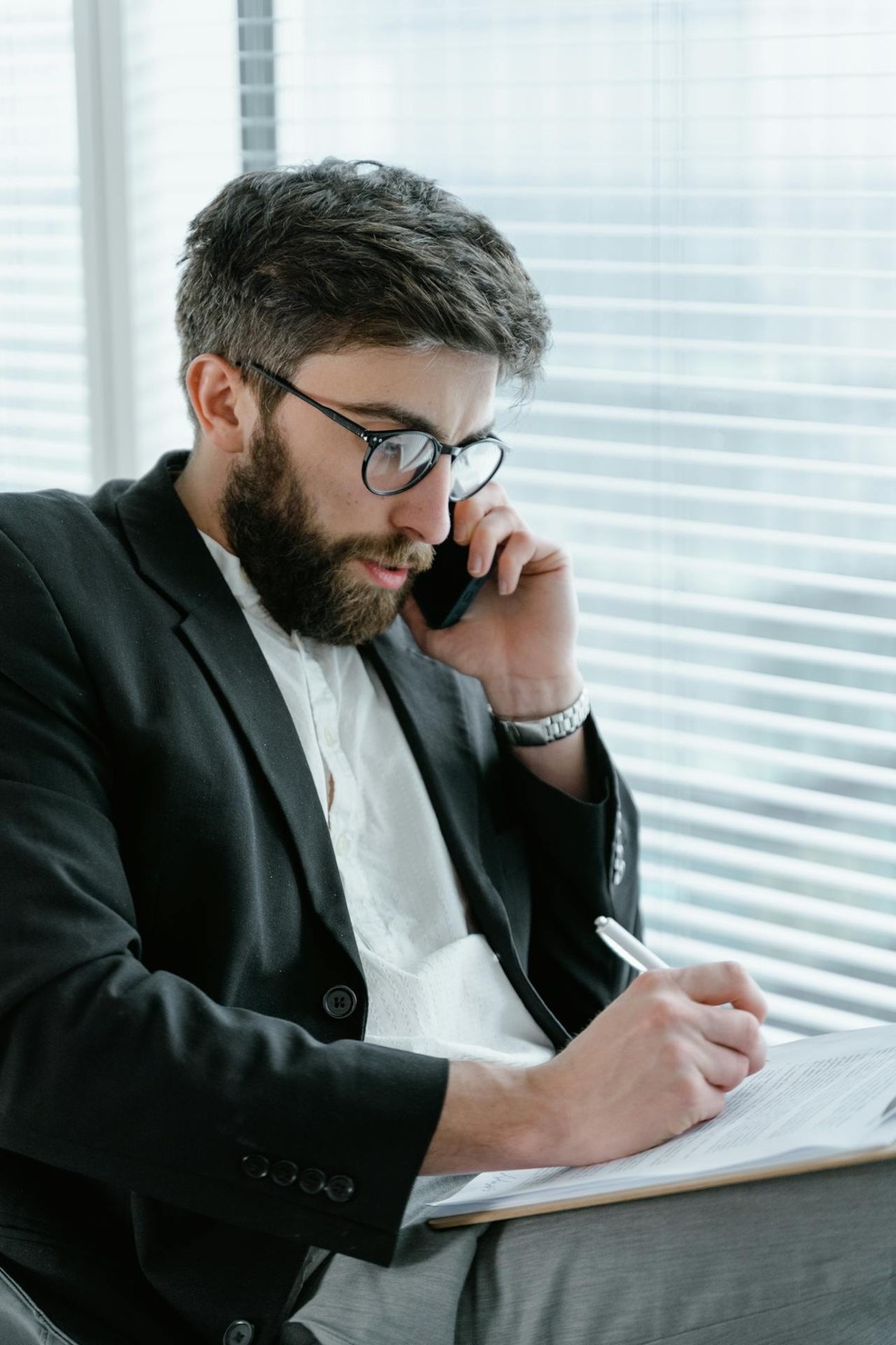A man talking on the phone while taking down notes