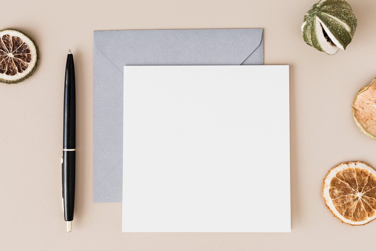 A photo of a pen next to an envelope and a piece of paper
