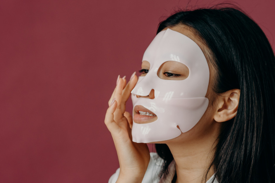 A woman touching her face with sheet mask.