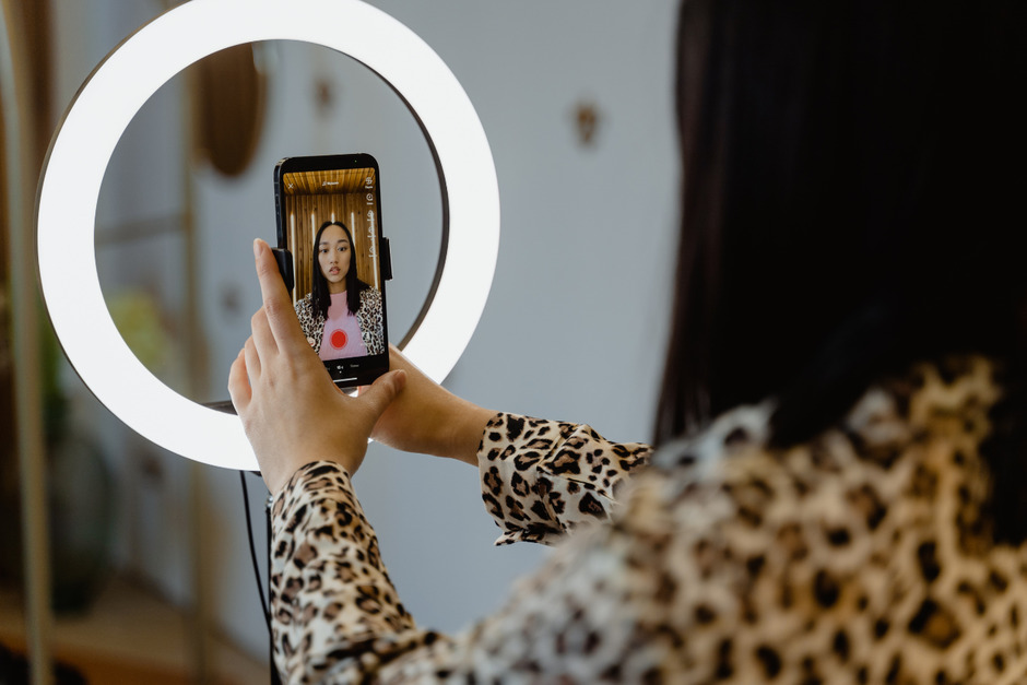 A woman using a smartphone and a ring light.