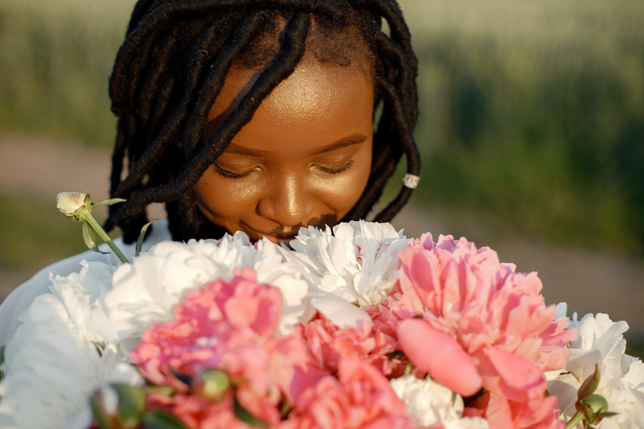 An African American girl joyfully sniffing flowers.
