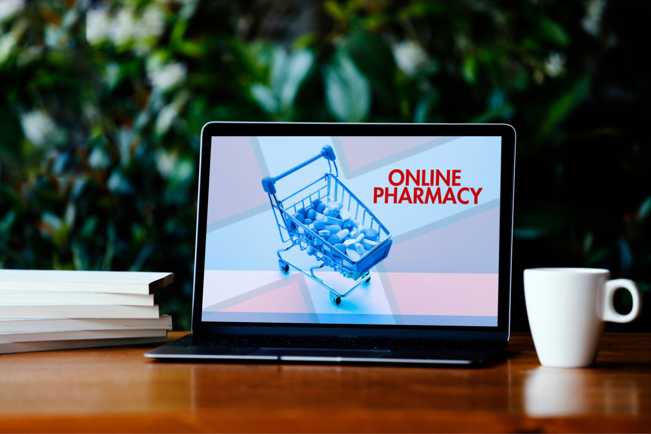 Cart filled with tablets displayed on laptop screen that reads online pharmacy.
