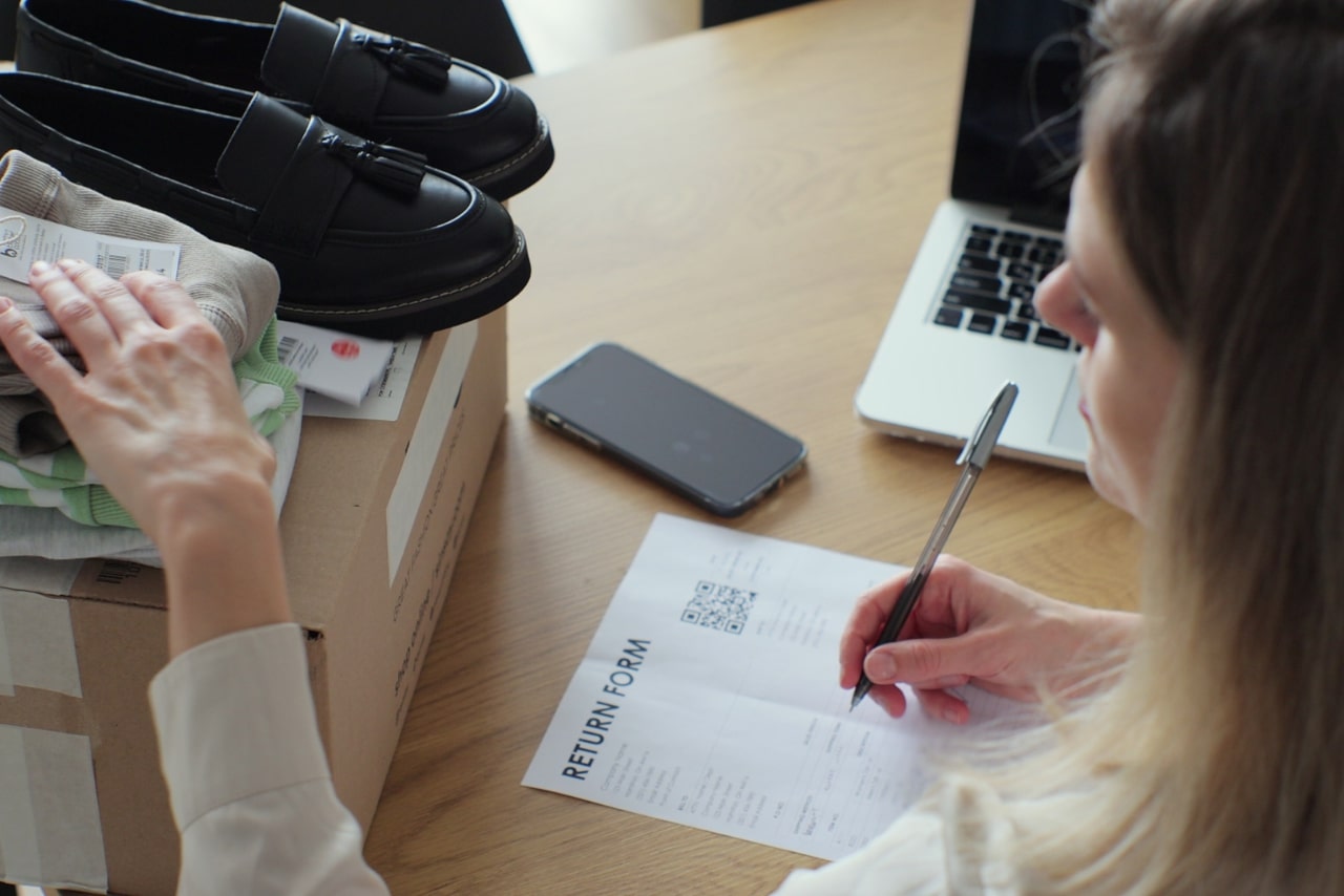 Close-up of a female customer writing on paper and filling out a form, wanting to return goods.
