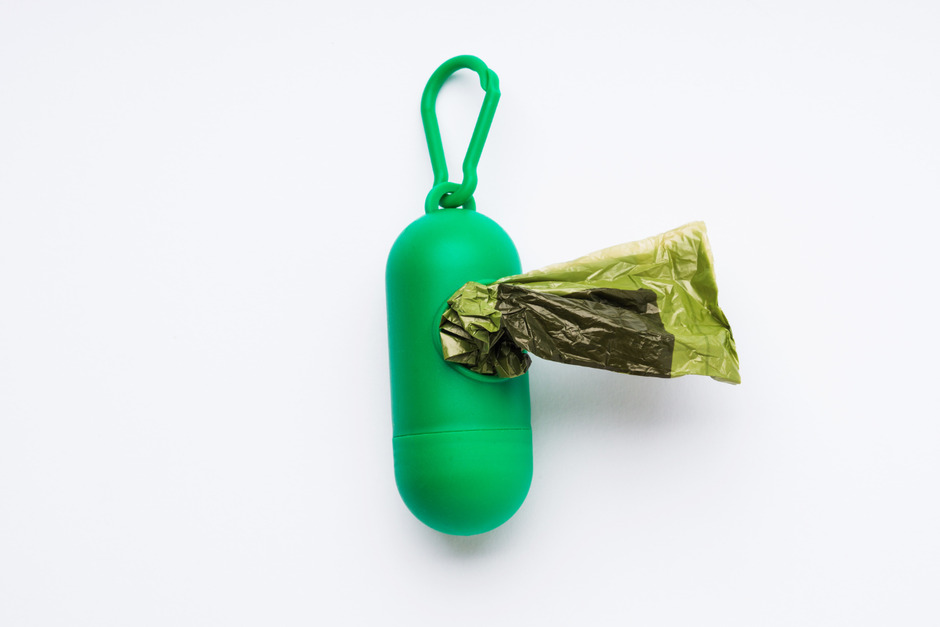 Compostable dog poop bags dispenser on white background.