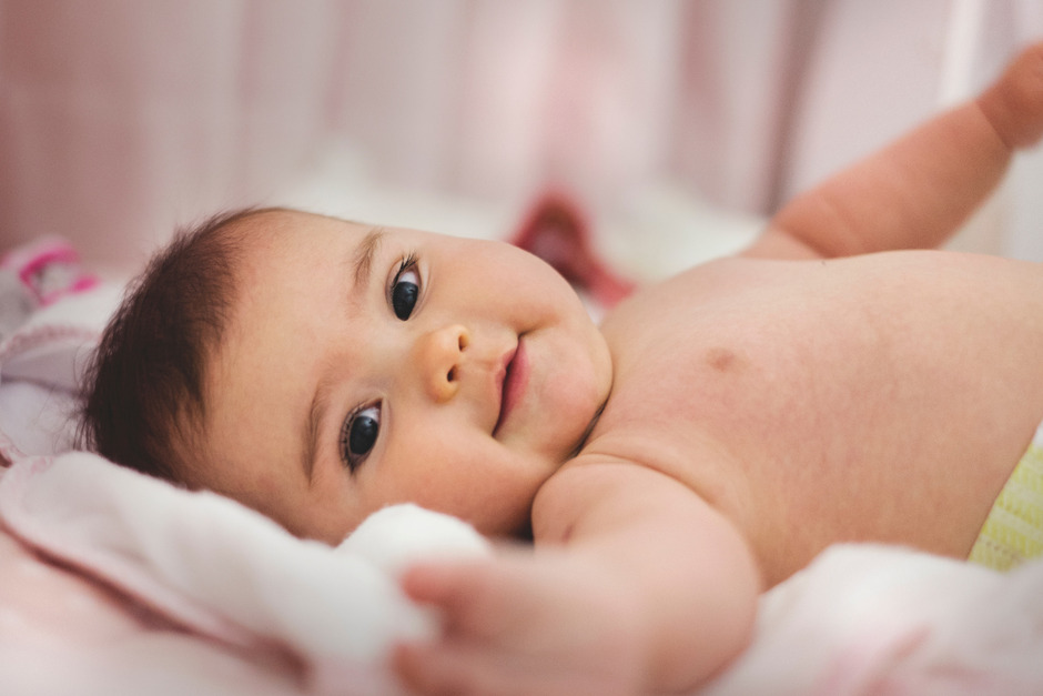 Cute baby lying on pink bed.