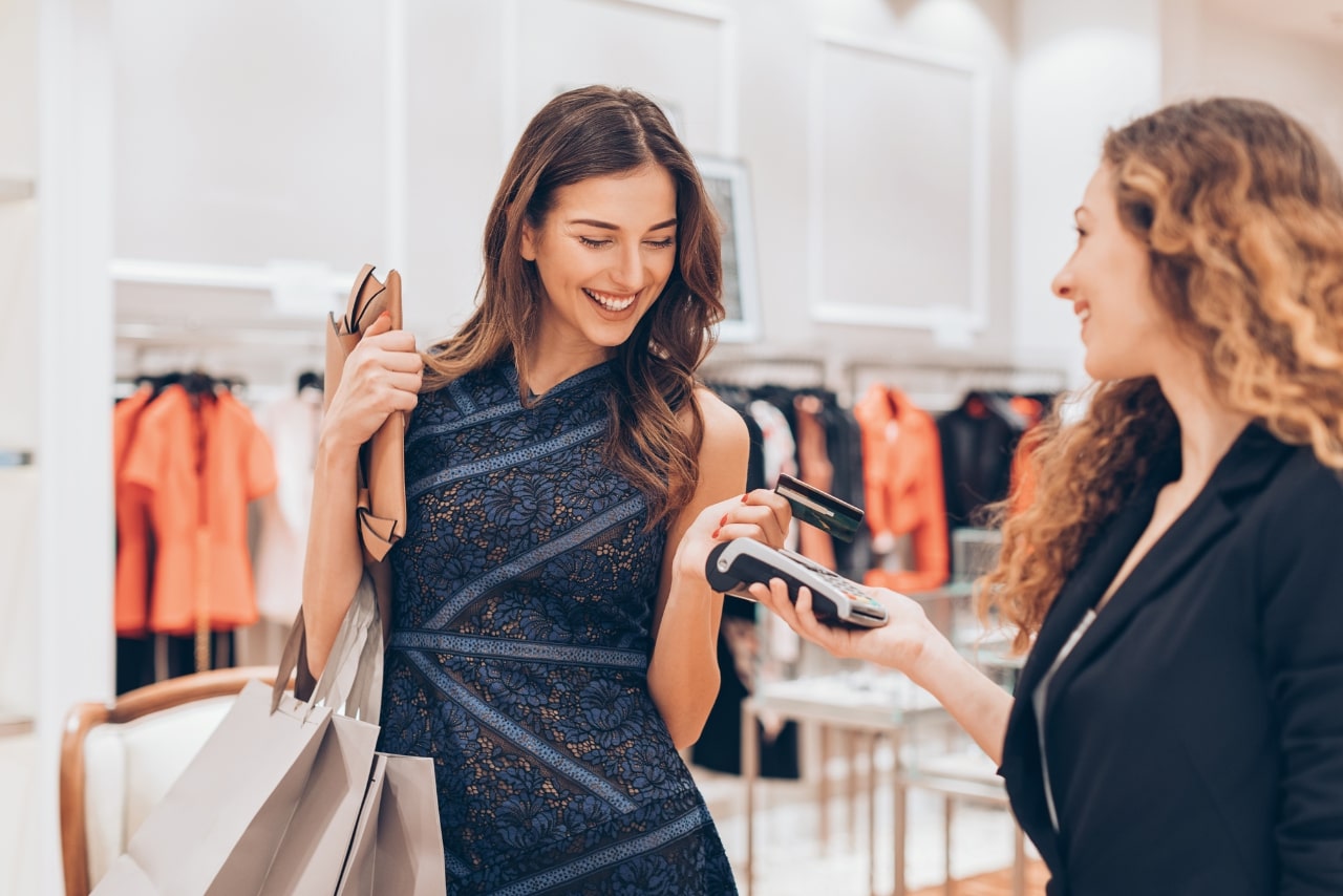 Fashionable woman making a contactless payment in a luxury store.